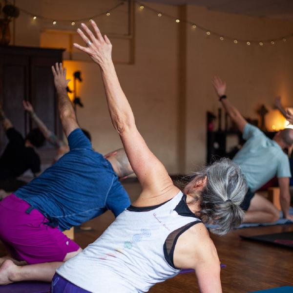 woman flexed forward on yoga mat with candles
